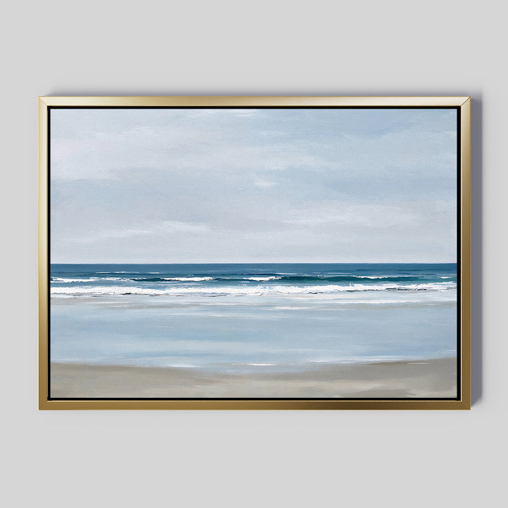 The Soft Tide Canvas Art – Horizontal features a calm beach with gentle waves and a muted blue and beige sky, set in a metallic gold frame. Ideal minimalist or coastal wall art to elevate your bedroom decor.