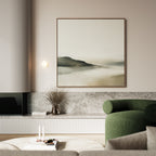 A modern living room featuring Soft Valley Canvas Art, a green upholstered chair, marble surfaces, a vase with dried branches, and candles on a low table. Neutral tones and minimalist decor create a calming atmosphere.