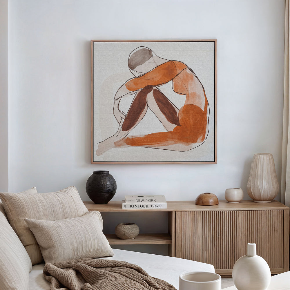 A minimalist living room features a beige sofa with neutral cushions, a wooden sideboard with vases and books, and the Solitude Canvas Art—an abstract portrait of a seated figure—framed above the sideboard for an elegant touch.