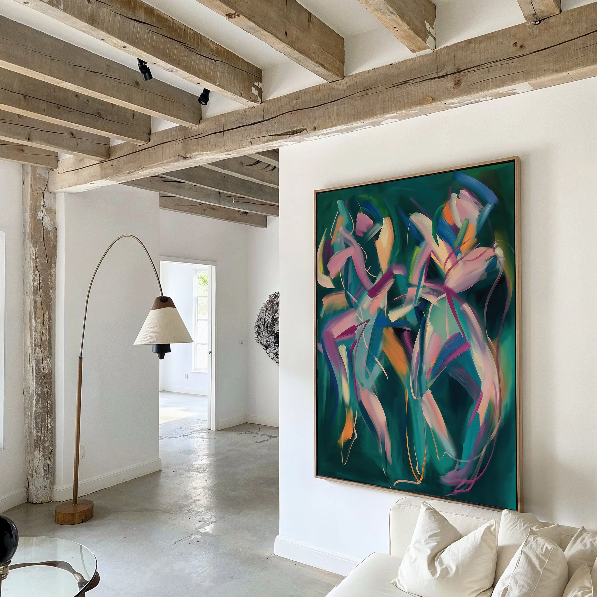 A modern living room with exposed wooden ceiling beams, white walls, a curved floor lamp, and the Spiralling Forms Abstract Canvas Art—a large piece featuring colorful swirling shapes on a green background above a white sofa.