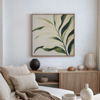 A minimalist living room with a beige sofa, cream pillows, and wooden sideboard is enhanced by the Spring Foliage Canvas Art—a green leaves print that adds a fresh touch to the modern decor on the white wall.