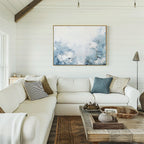 A bright living room with white shiplap walls, modern accents, a large white sectional with throw pillows, a rustic wooden coffee table, and the Spring Hues Canvas Art – Horizontal displayed above the sofa.