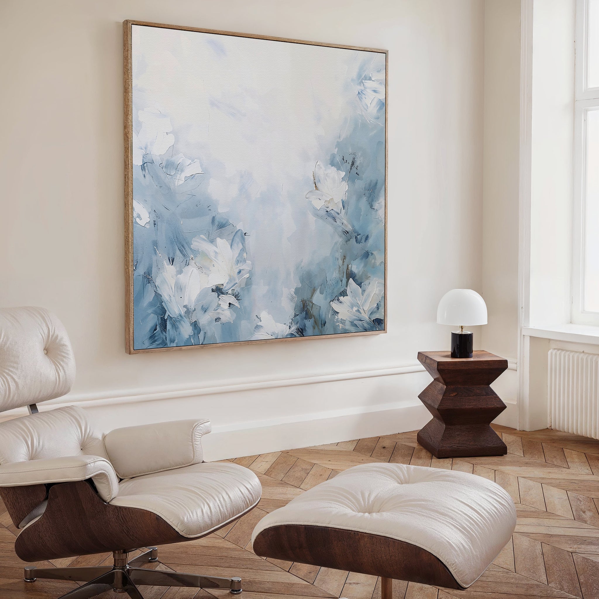 A modern, minimalist living room featuring a cream leather lounge chair with ottoman, a geometric wooden side table with a white lamp, and the vibrant Spring Hues Abstract Canvas Art energizing the space.
