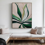 A modern living room with light wood furniture and neutral cushions features Springs Essence Abstract Canvas Art—a large painting of green leaves on a pale background—hanging on a white wall above a corner bench.