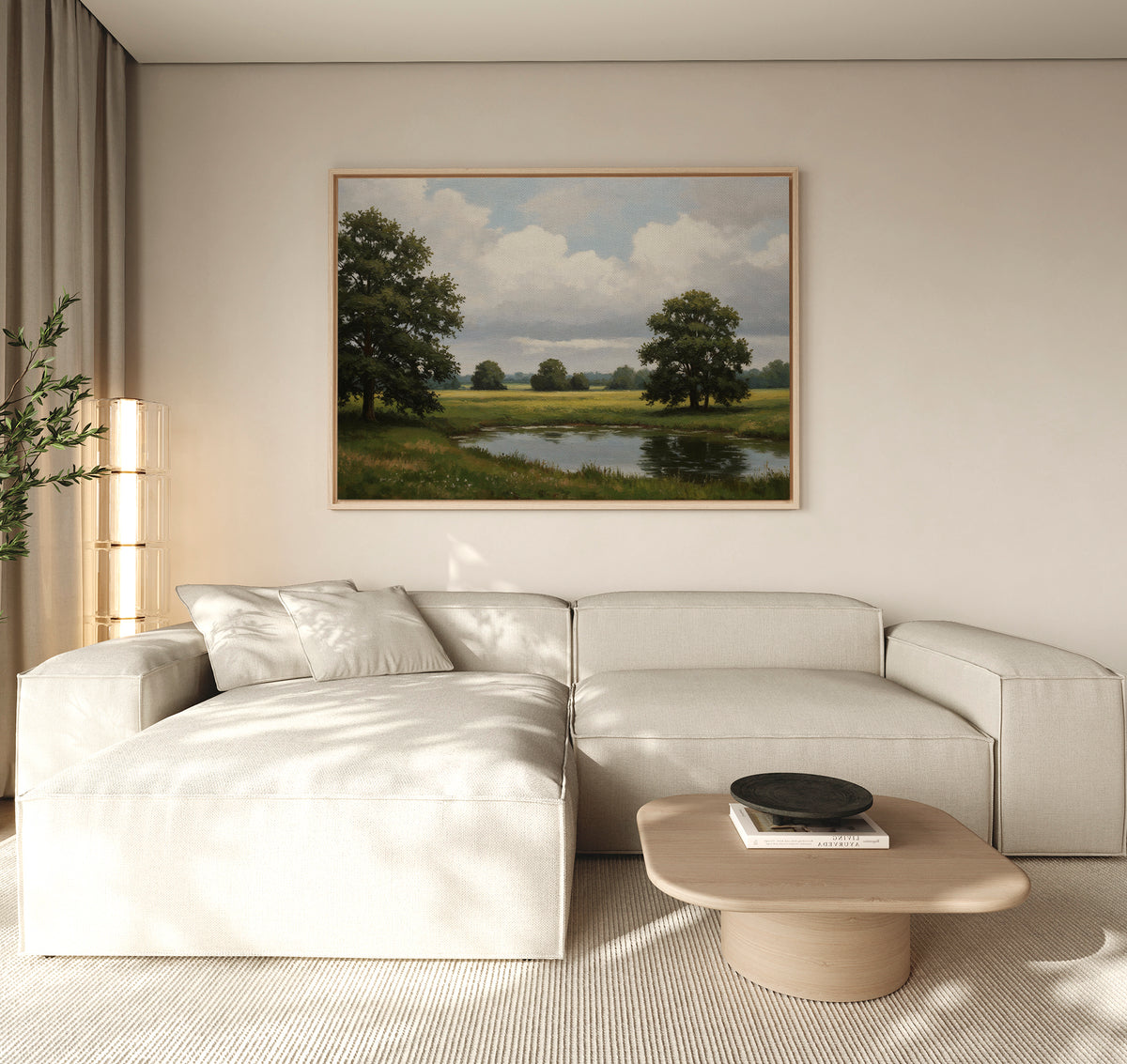 A modern living room with a light beige sectional sofa, wooden coffee table, and the Still Grove Canvas Art—a large landscape painting of trees and a pond—hanging above the sofa. Natural light streams in through curtained windows.