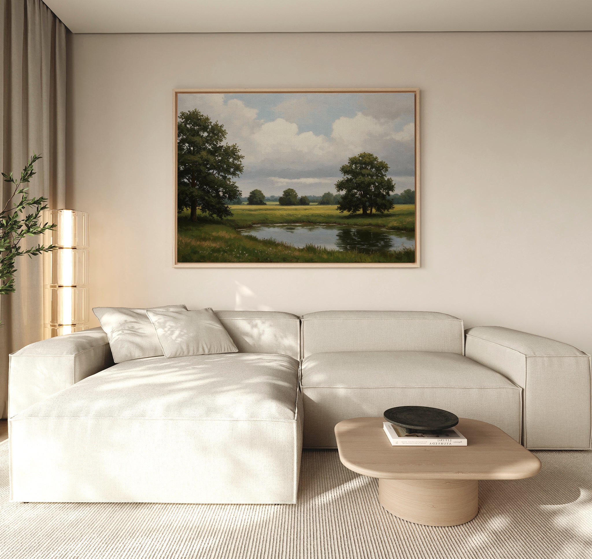 A modern living room with a light beige sectional sofa, wooden coffee table, and the Still Grove Canvas Art—a large landscape painting of trees and a pond—hanging above the sofa. Natural light streams in through curtained windows.