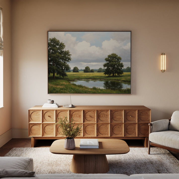 A cozy living room with a light sofa, wooden coffee table, and sideboard. The Still Grove Canvas Art hangs above the sideboard. A small vase with flowers sits on the coffee table.