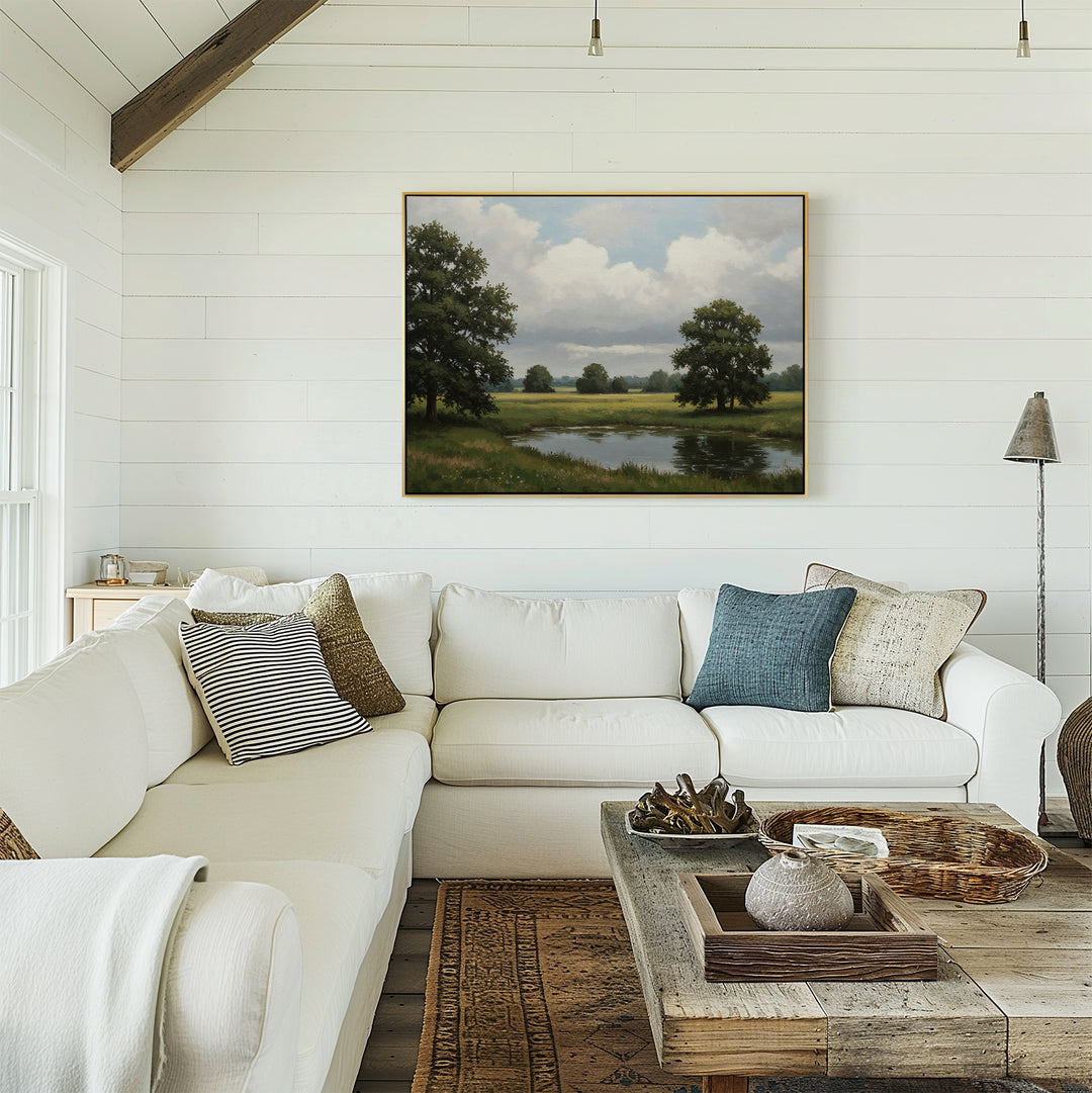 A bright living room with a white sectional sofa, assorted pillows, a rustic wooden coffee table, and the Still Grove Canvas Art hanging on the white shiplap wall.