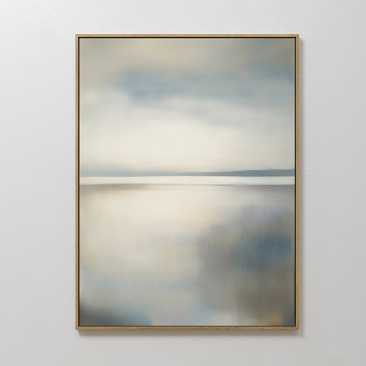 The Still Horizon Canvas Art, a framed abstract painting with soft blue, gray, and beige tones evoking a calm seascape, hangs on a white wall—perfect minimalist wall art for any room.