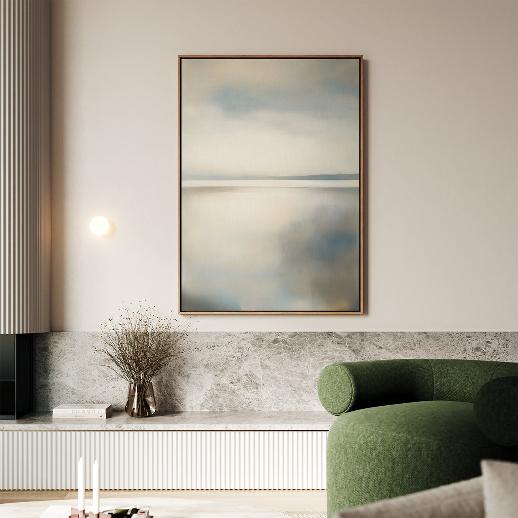 A minimalistic living room featuring the Still Horizon Canvas Art in soft blues and greys, a curved green sofa, built-in shelving with a vase of dried branches, and neutral-toned walls and decor.