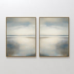 The Still Horizon Set of 2 features framed abstract art depicting a tranquil shoreline with calm water and cloudy skies in muted blue, gray, and beige. This minimalist wall art adds a peaceful, Nordic Park-inspired vibe to any space.