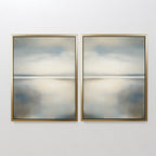 The Still Horizon Set of 2 features framed abstract paintings side by side, showing calm water and sky in muted blue, beige, and gray with gold frames. This minimalist wall art brings a serene shoreline vibe to your space.