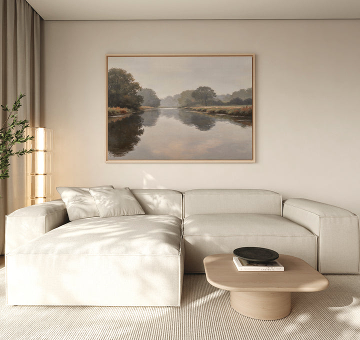A modern living room with a light beige sectional, wooden coffee table with black bowl, and the Still Riverbank Canvas Art – Horizontal on a neutral wall. Natural light brightens the space.