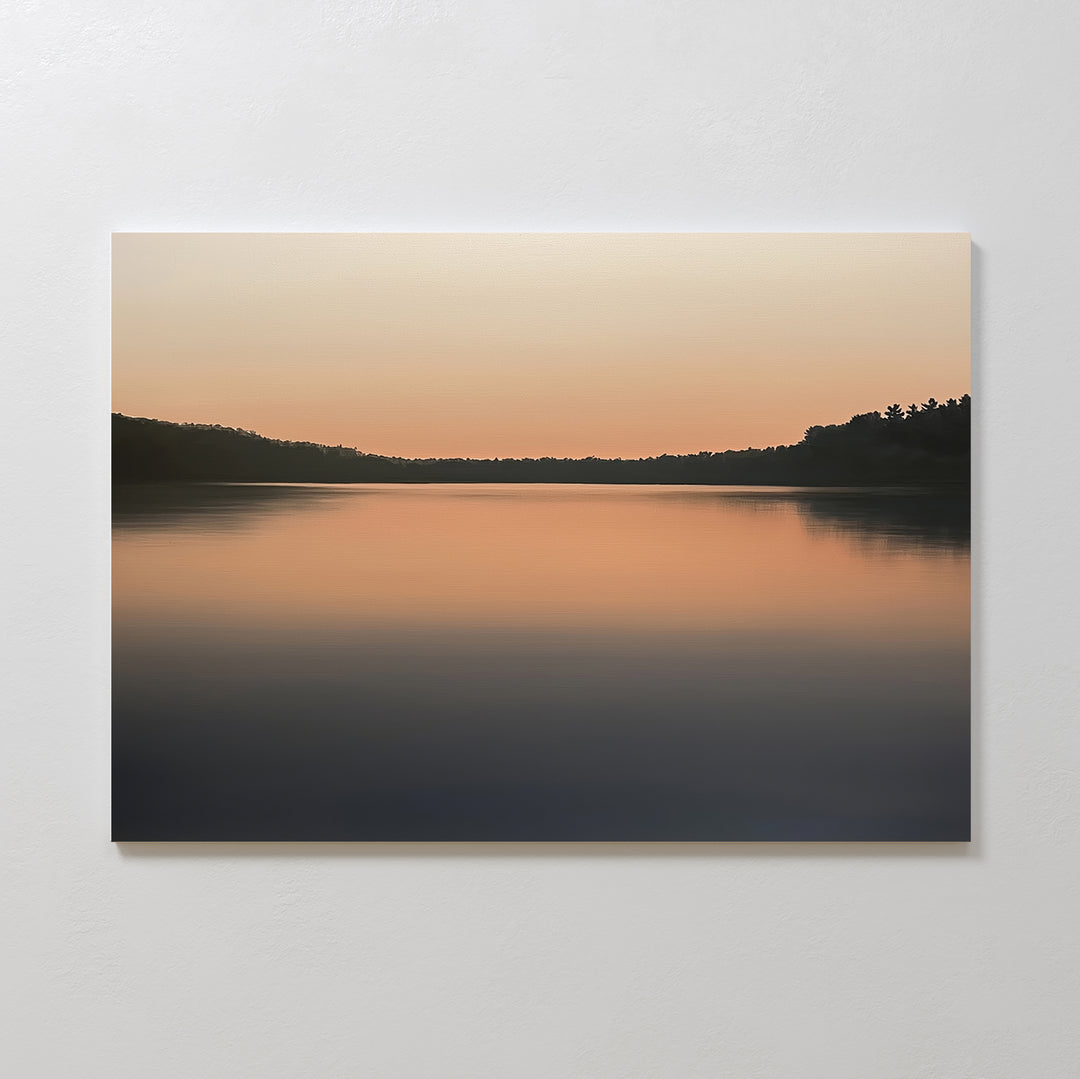 The Still Waters Canvas Art – Horizontal features a minimalist photograph of a calm lake at sunset, with smooth water reflecting orange hues and silhouetted trees for peaceful, serene bedroom decor.