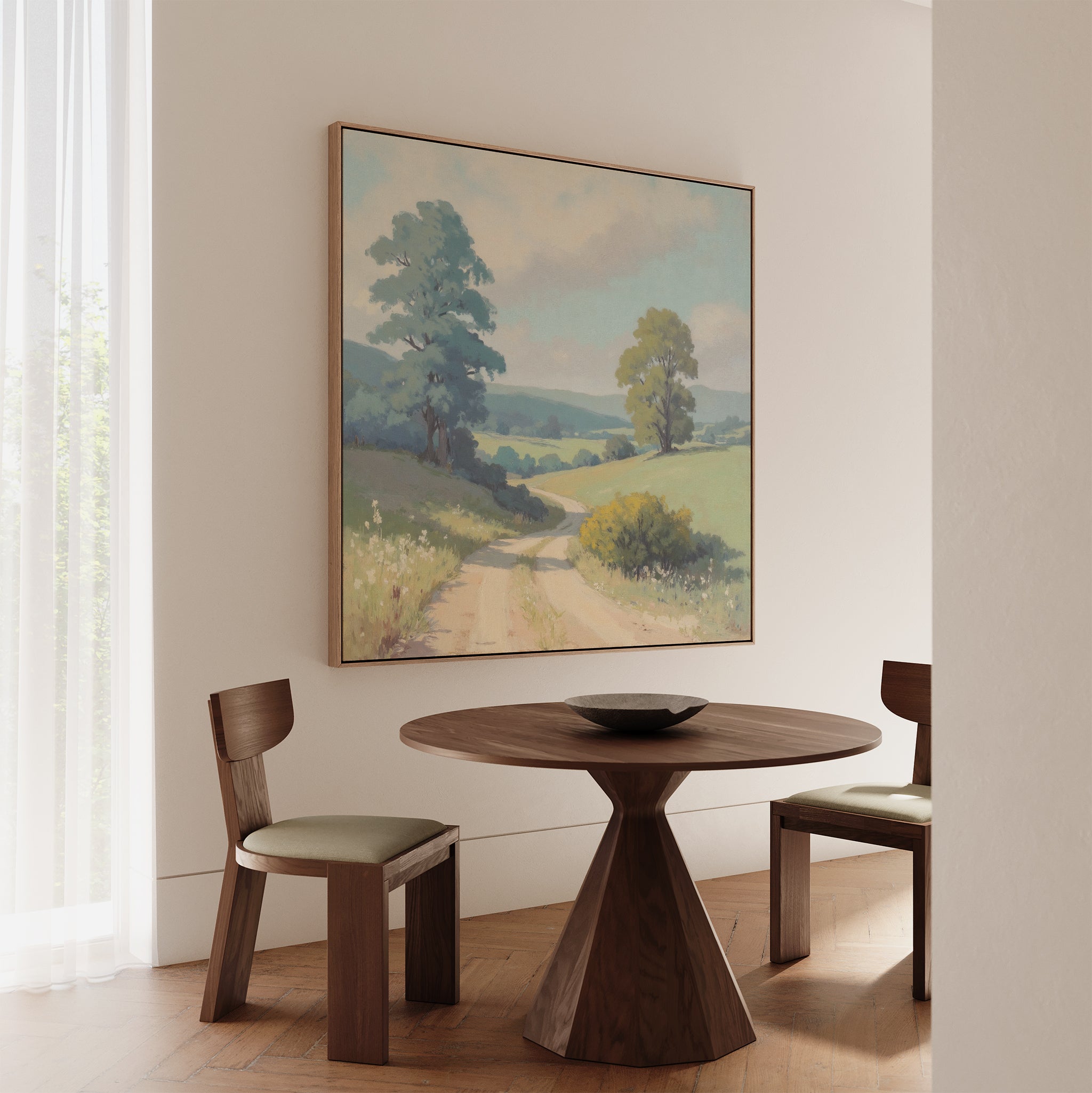 A small, modern dining area features a round wooden table, two wooden chairs, and rustic wall art—a large Summer Dale Canvas Art print—hanging on the wall. Soft light filters through a sheer white curtain.