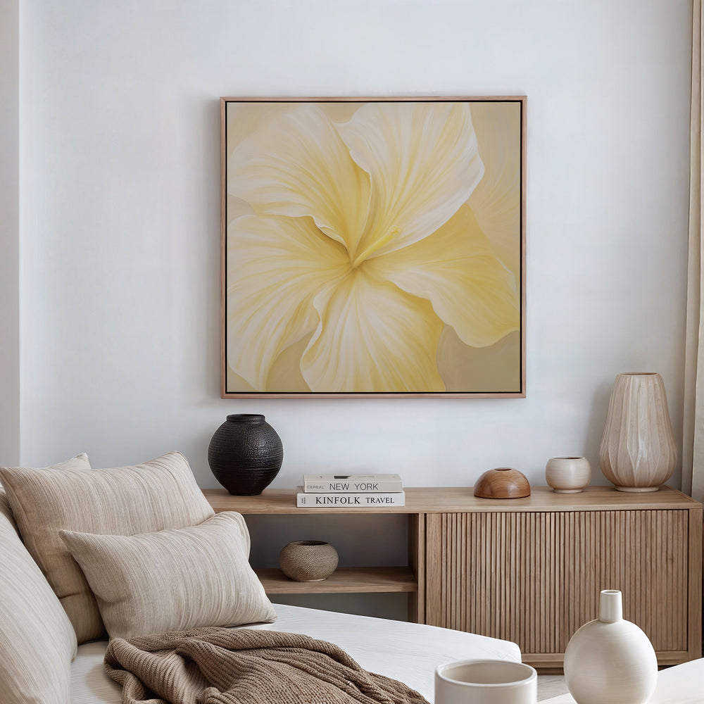 A minimal living room features a beige couch, neutral cushions, wooden sideboard, vases, books, and is elevated by modern decor highlighted by the Sunlight Curve Canvas Art—a striking wall piece showcasing a pale yellow flower.