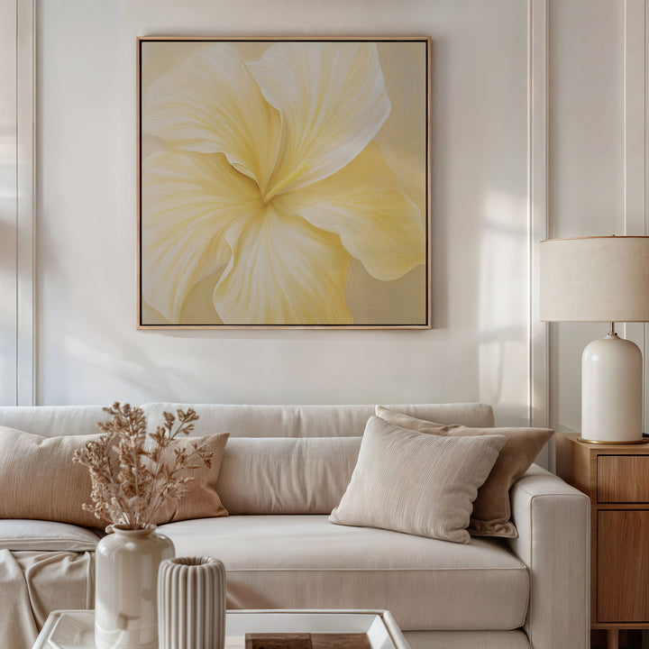 A modern living room with a beige sofa, neutral pillows, and a side table with a cream lamp. Dried flowers and the Sunlight Curve Canvas Art in soft yellow complete the minimalist décor above the sofa.