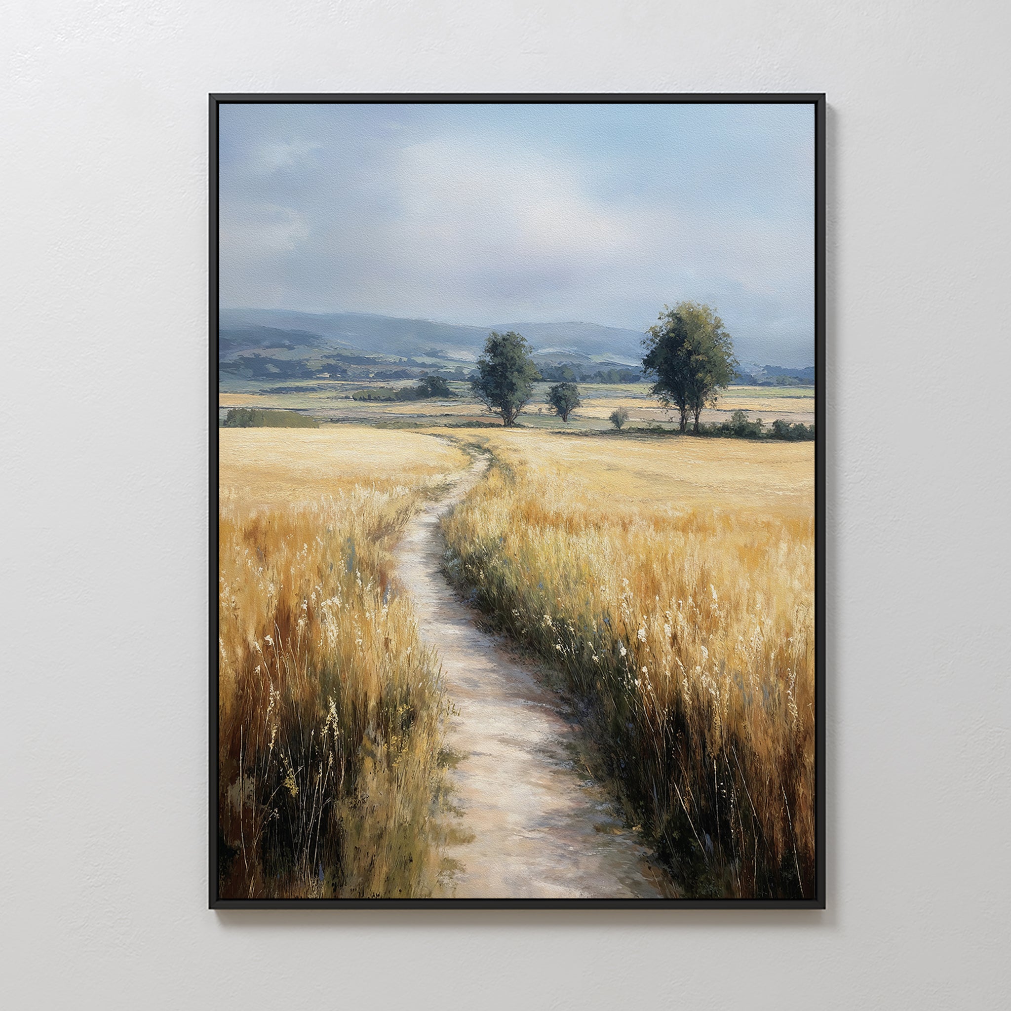 The Sunlit Passage Canvas Art features a framed, nature-inspired print of a dirt path through golden wheat toward distant trees and blue mountains under a cloudy sky, bringing serenity and natural beauty to any space.