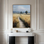 A marble console table with modern decor sits against a white paneled wall. Above it hangs the Sunlit Passage Canvas Art, depicting a country path winding through golden fields toward distant trees and hills under a blue sky.