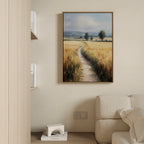 A cozy living room with a beige sofa, minimalist shelves, and the Sunlit Passage Canvas Art—a landscape of a golden field with trees and mountains—hanging on a light-colored wall.
