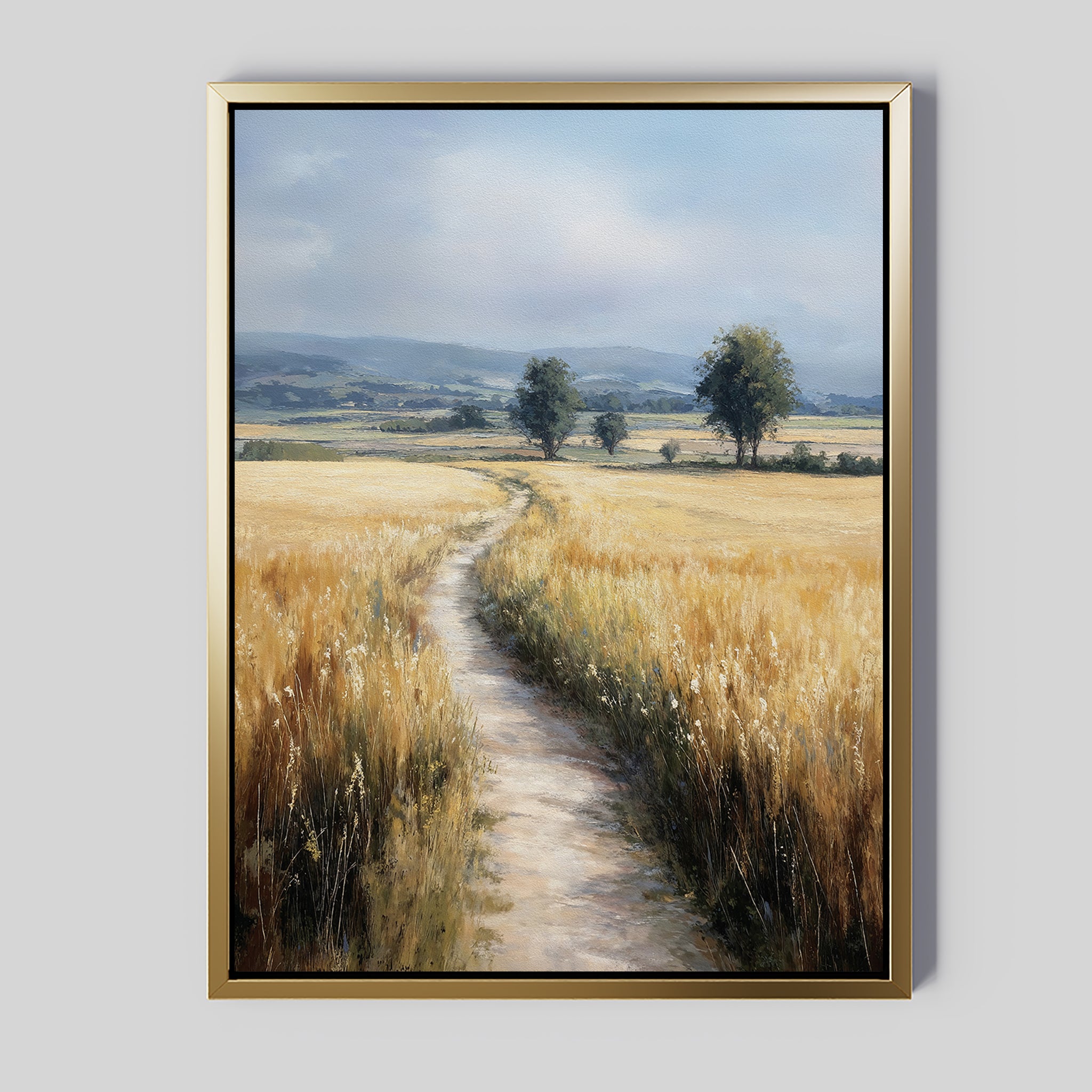 The Sunlit Passage Canvas Art is a large, framed print depicting a country path through golden fields toward two distant trees under a cloudy sky. It features a gold frame with a minimalist gray background for stylish, nature-inspired wall decor.