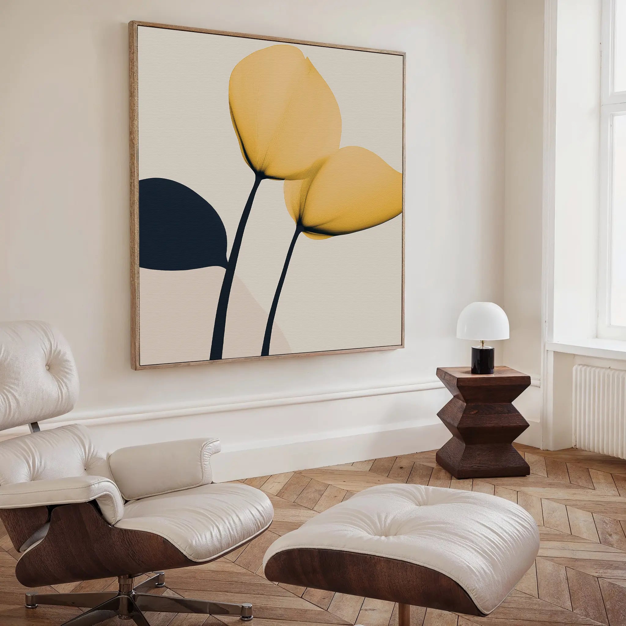 A modern living room with a white lounge chair and ottoman, a geometric wooden side table with a small white lamp, and the Sunny Flora Canvas Art featuring three abstract yellow and black floral shapes on the wall.