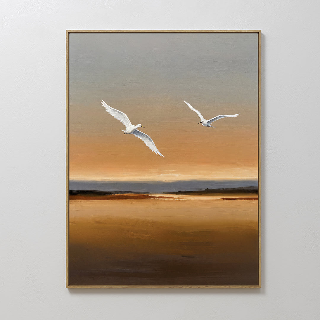 Sunset Flight Canvas Art features two white birds soaring above a calm brown and orange landscape beneath a muted gray sky, all in a thin light wooden frame—an ideal minimalist piece to elevate your bedroom decor.