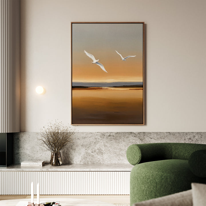 A modern living room features a green curved sofa, marble shelf, and the Sunset Flight Canvas Art showing two white birds over a golden-brown sunset. Dried flowers and candles add decorative touches to the shelf.