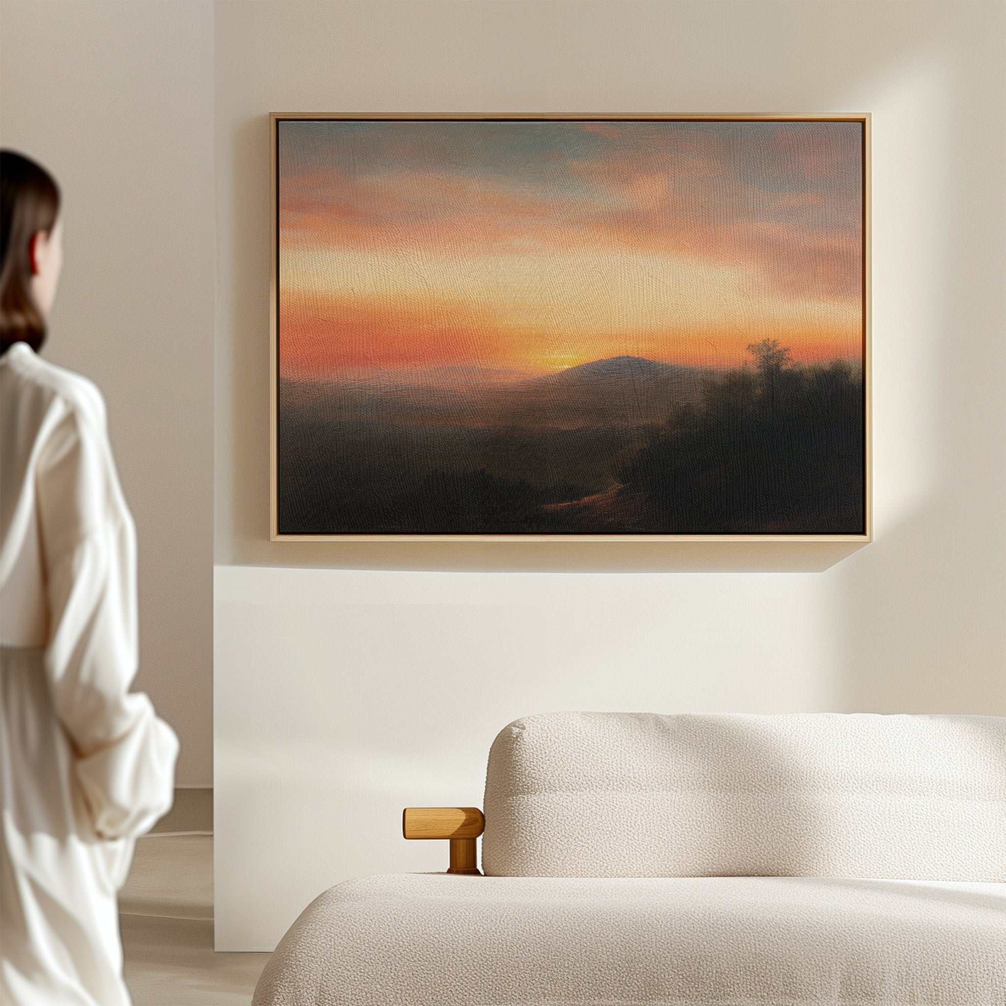 A person stands in a modern, light-filled room admiring the Sunset Reflection Canvas Art, a serene landscape print of a mountain sunset hanging above a beige sofa—an ideal piece of sunset wall art.
