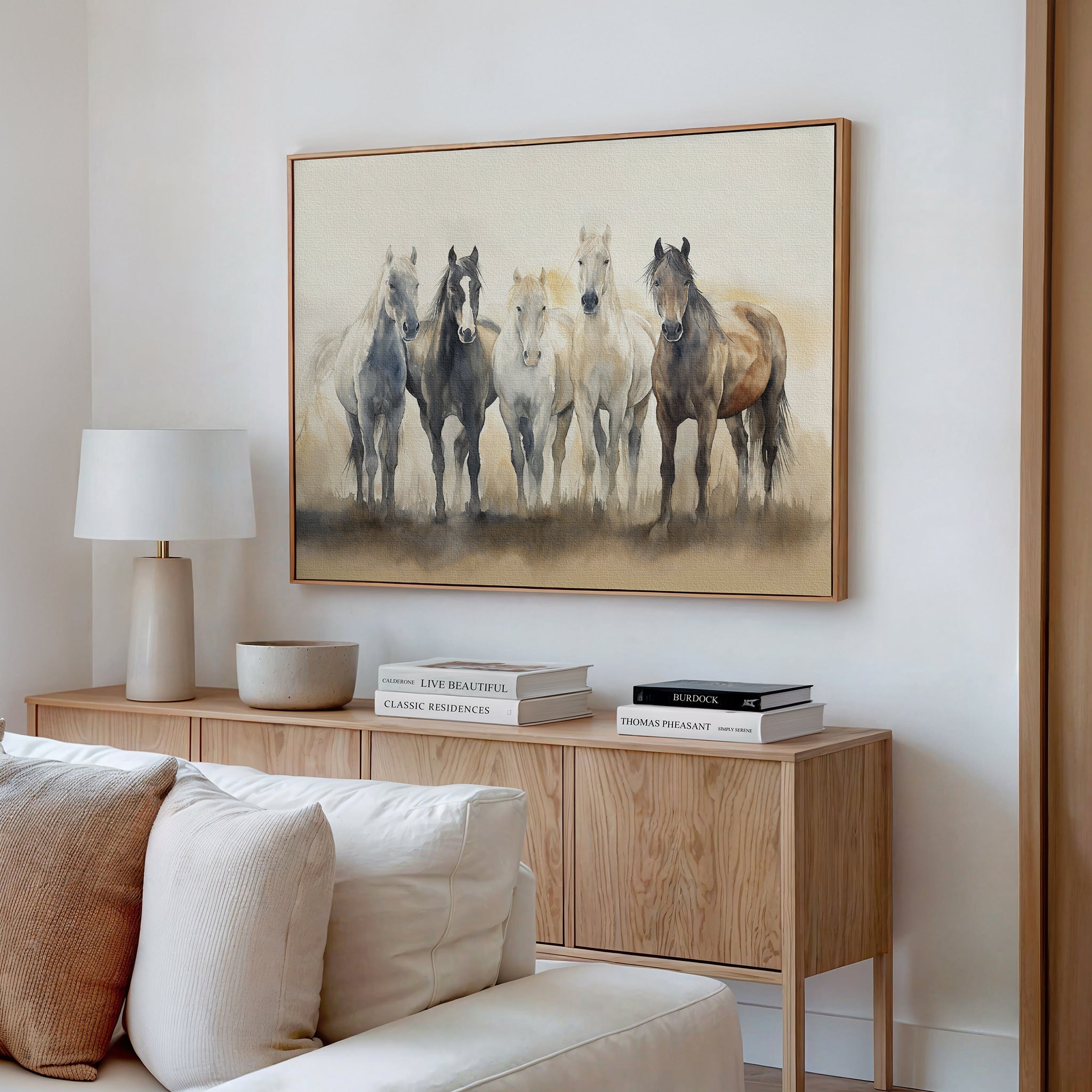 A cozy living room with a light wood sideboard, white table lamp, stacked books, and decorative bowl. Above the sideboard, the Sunset Ride Canvas Art adds a charming touch to the nature-inspired decor.