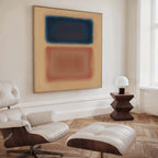 A minimalist room with a white leather lounge chair, ottoman, geometric wooden side table, small white lamp, and modern interiors featuring the Sunset Vapor Canvas Art with blue and peach rectangles on a beige wall.