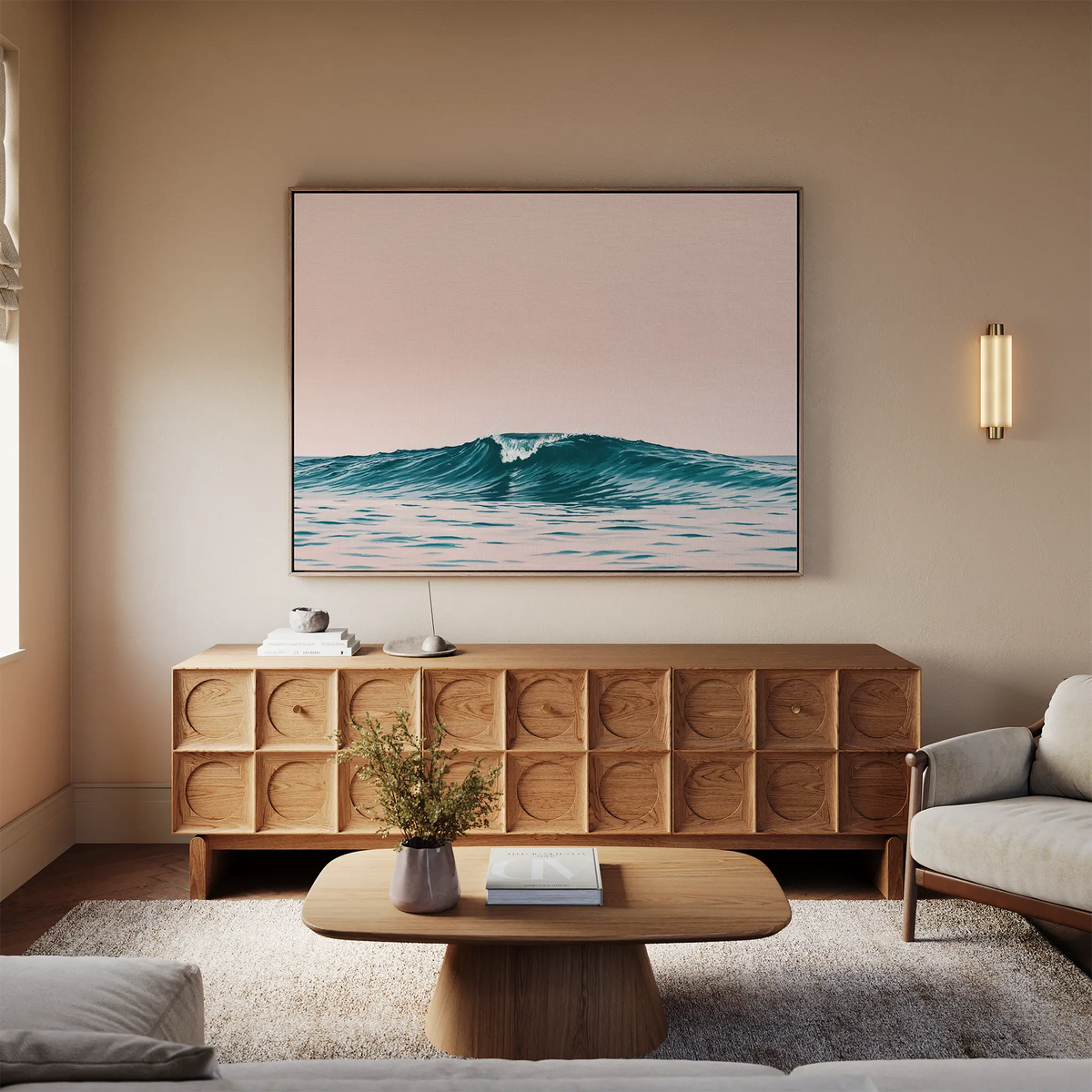 A cozy living room with neutral tones features a wooden sideboard, a light sofa, a coffee table with a vase, and beach-inspired wall decor—a large framed Sunset Wave Canvas Art—above the sideboard.