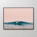 The Sunset Wave Canvas Art features a single blue ocean wave with gentle ripples under a soft pink sky, adding beach-inspired decor to any light grey wall.