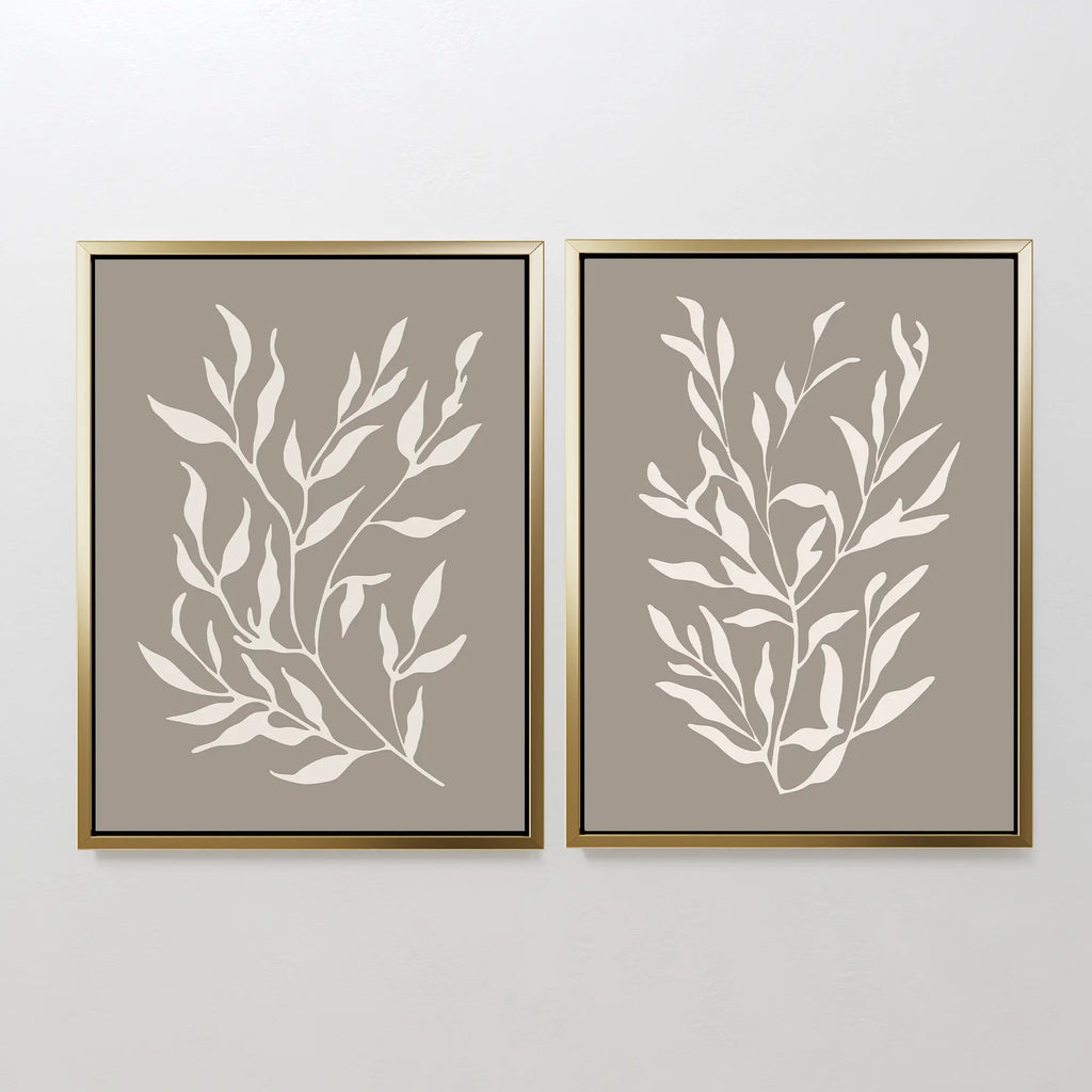 The Taupe Botanical Set of 2 features minimalist white leafy designs on taupe backgrounds, each print framed in gold with black inner borders—ideal for modern spaces and contemporary interiors.