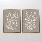 The Taupe Botanical Set of 2 features minimalist white leafy designs on taupe backgrounds, each print framed in gold with black inner borders—ideal for modern spaces and contemporary interiors.