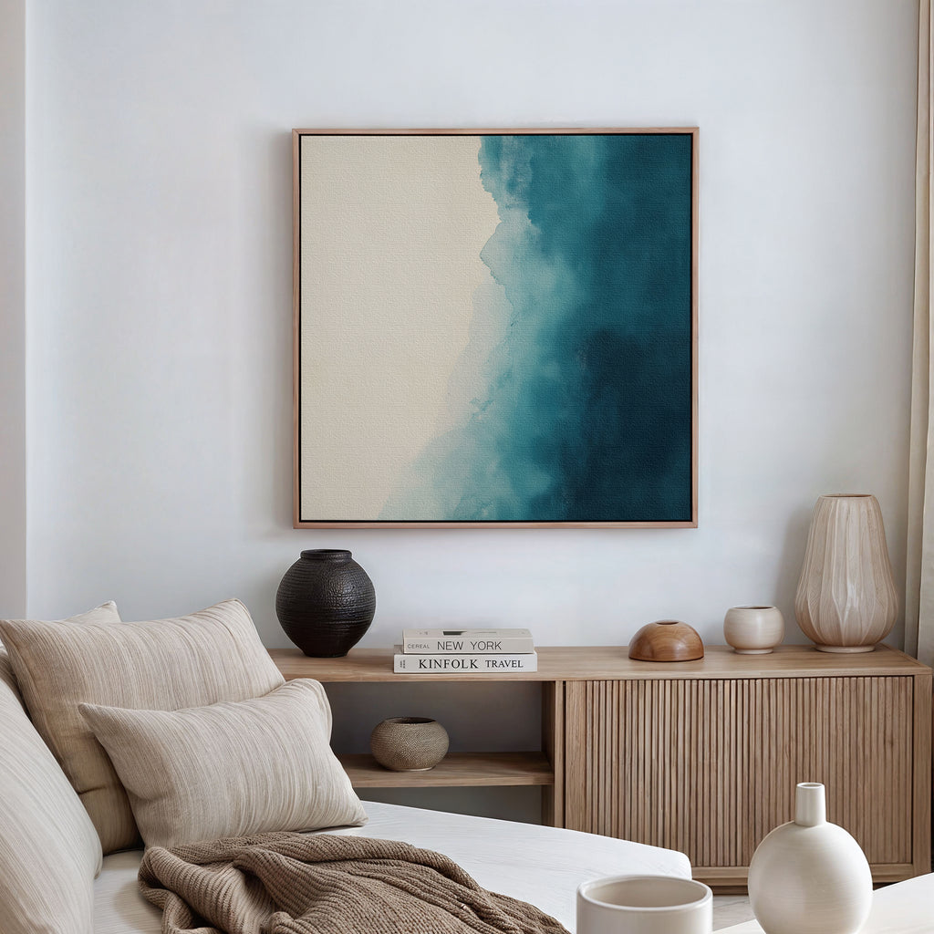 A modern living room with a beige sofa, neutral pillows, a wooden sideboard topped with decor, and the Teal Tide Canvas Art featuring blue and cream tones displayed on the wall.