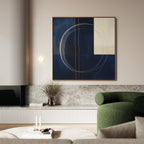 Modern living room featuring The Orbit Canvas Art with bold blue and cream circular patterns above a green curved armchair, marble console, minimalist decor, and books—a perfect accent for any modern home.