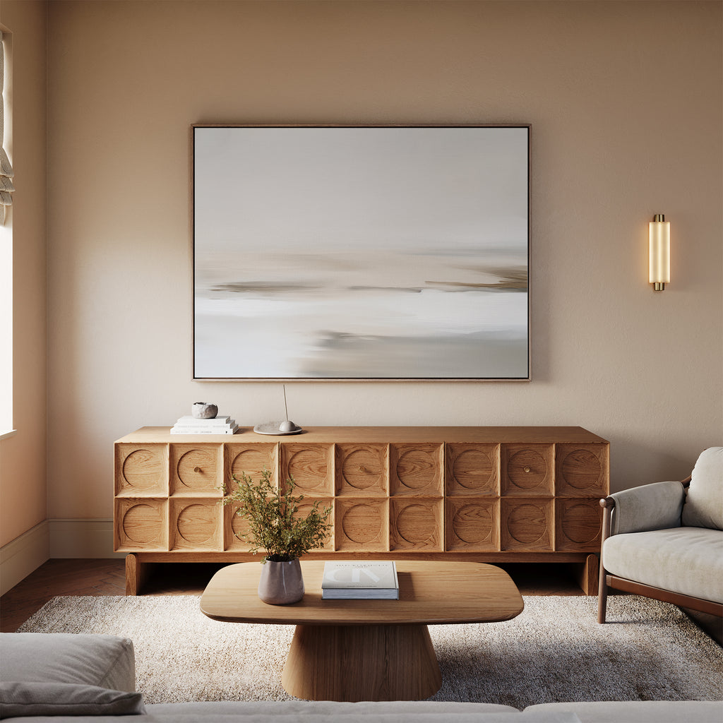 A minimalist living room with a light wooden coffee table, geometric-patterned sideboard, neutral sofa, beige rug, and Tranquil Shifts Canvas Art – Horizontal as the focal point above the sideboard completes this stylish decor.