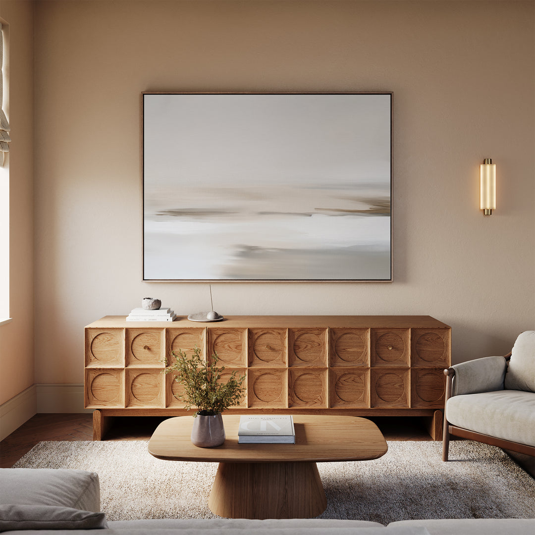 A minimalist living room with a light wooden coffee table, geometric-patterned sideboard, neutral sofa, beige rug, and Tranquil Shifts Canvas Art – Horizontal as the focal point above the sideboard completes this stylish decor.