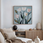 A cozy, minimal living room with a light wood sideboard, neutral decor, books, and minimalist wall art—Tulip Harmony Canvas Art—above a beige sofa with striped pillows, perfect for elegant living room decor.
