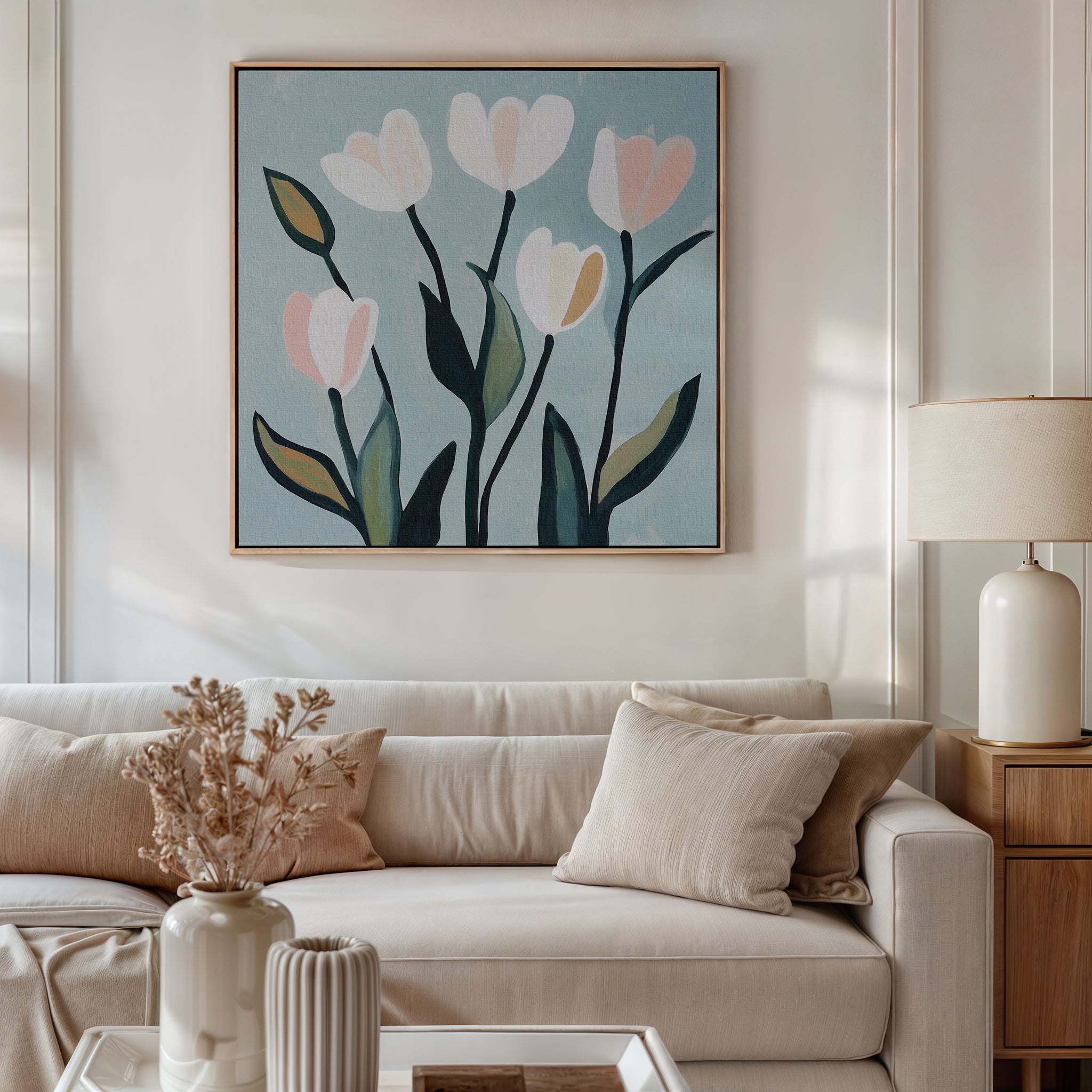 A modern living room with a beige sofa, neutral pillows, dried flowers in a vase, a table lamp, and Tulip Harmony Canvas Art. The cozy, uncluttered decor is perfect for those who appreciate simple living room style.