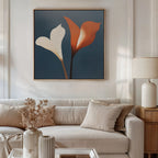 A modern living room with a beige sofa, cream pillows, and a side table with a lamp. Twin Blooms Canvas Art hangs as wall decor, showing two stylized flowers—one white, one orange—on blue. Vase with dried flowers beside.