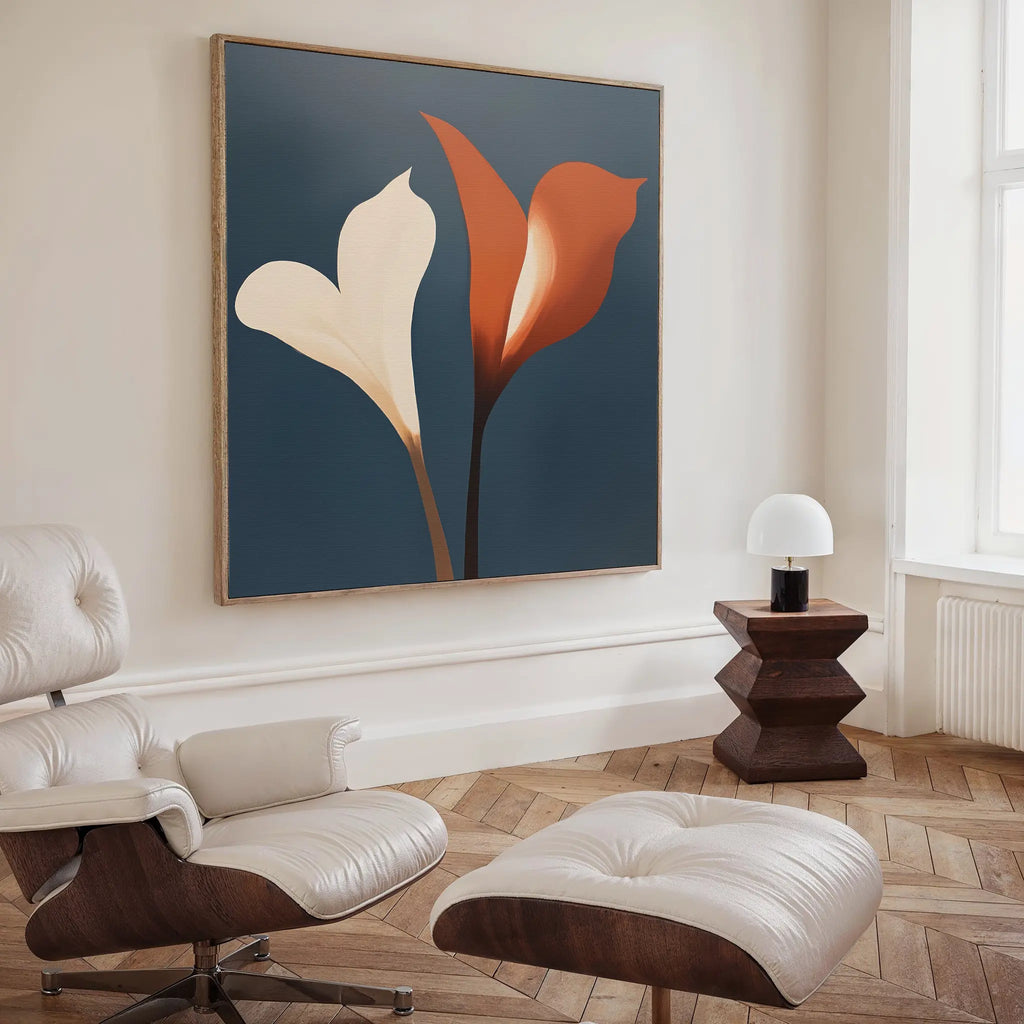 A modern living room with a white leather chair and ottoman, geometric wooden side table, small white lamp, and striking Twin Blooms Canvas Art—an abstract botanical print featuring cream and orange flowers on a blue background.