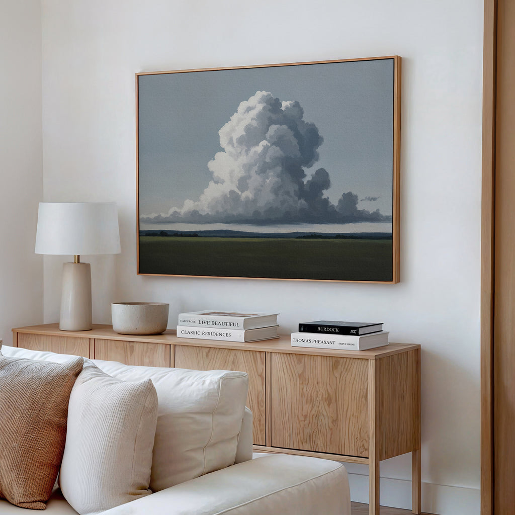 A minimalist living room with a wooden sideboard, white lamp, neutral decor, and books. The Uplifted Sky Canvas Art hangs above the sideboard, bringing an elegant touch of minimalist sky-inspired wall art to the space.
