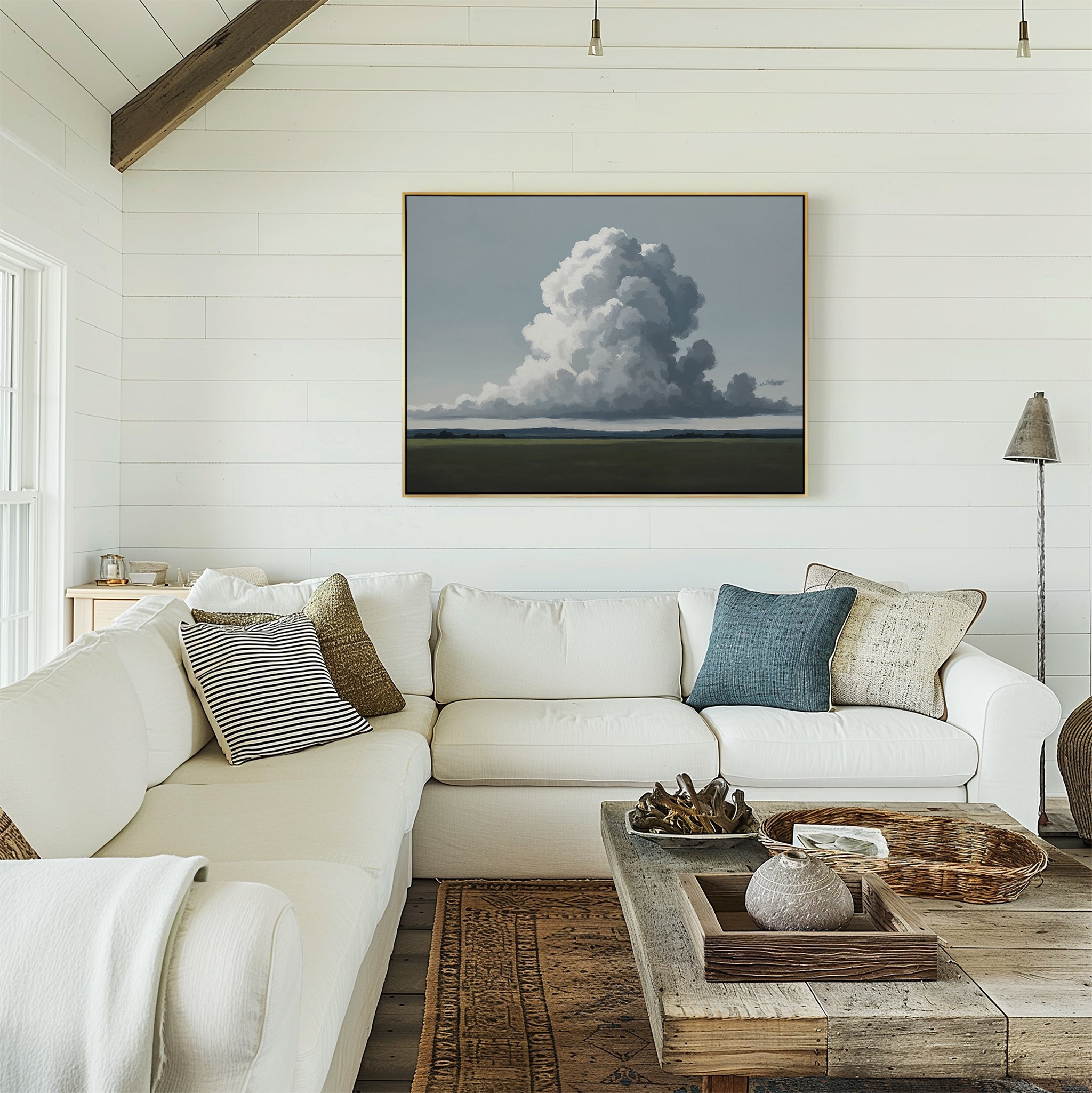 Bright living room with white shiplap walls, a large white sectional sofa with assorted pillows, rustic wood coffee table, woven baskets, and the Uplifted Sky Canvas Art featuring a cloud formation above the couch.