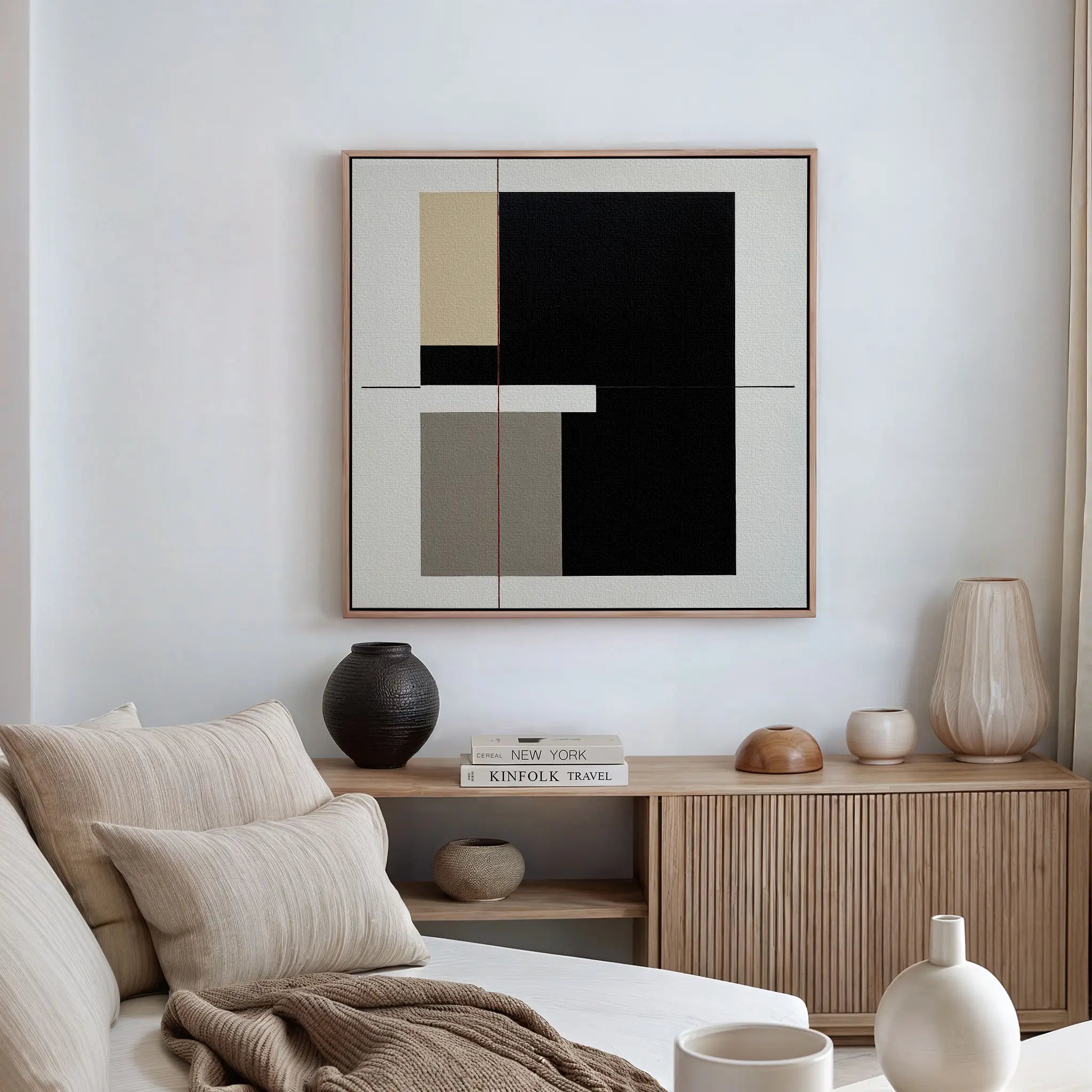 A modern, minimalist living space featuring a beige sofa, neutral cushions, wooden sideboard, ceramic vases, stacked books, and the Urban Balance Canvas Art with bold black, white, beige, and gray geometric blocks displayed above.