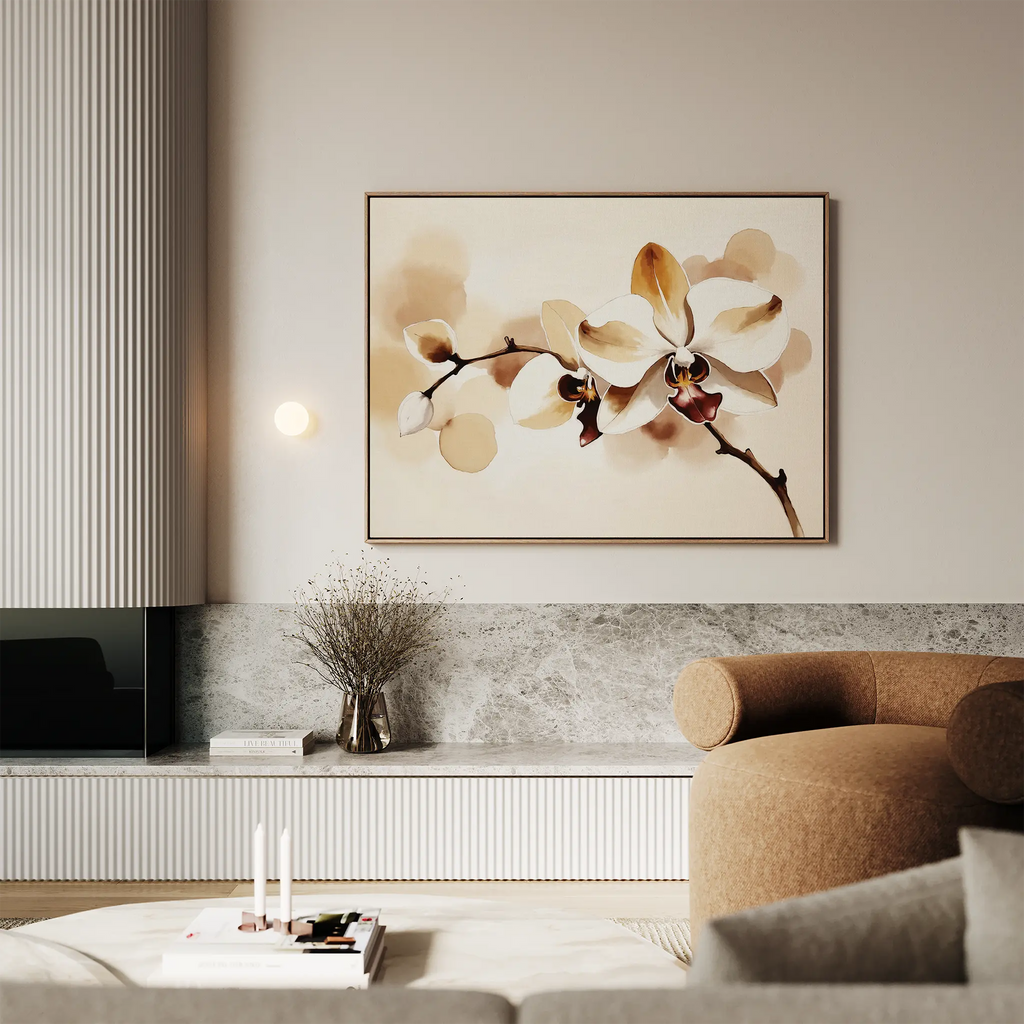 A modern living room with a beige sofa, marble accents, a vase of dried flowers, and elegant wall décor featuring the Vanilla Bloom Canvas Art—a large floral print of white and yellow orchids.