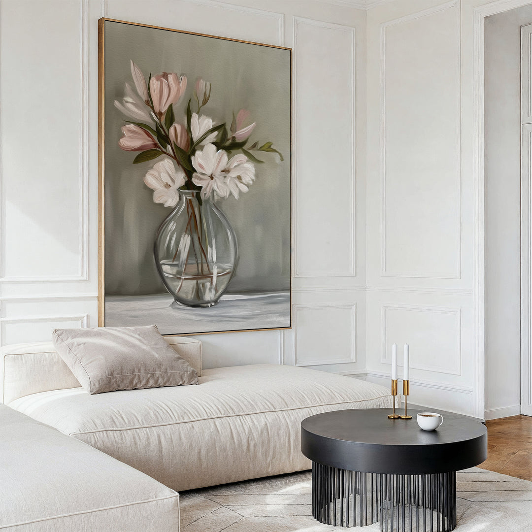 A modern living room features a cream sofa, black round coffee table, and the elegant Vase & Grace Canvas Art showcasing white and blush flowers in a glass vase, creating serene and stylish decor.