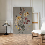The Velvet Petals Canvas Art leans against a white paneled wall near an empty frame. A black round table with candles and books sits nearby, and a white cushioned chair is placed on the herringbone wood floor.