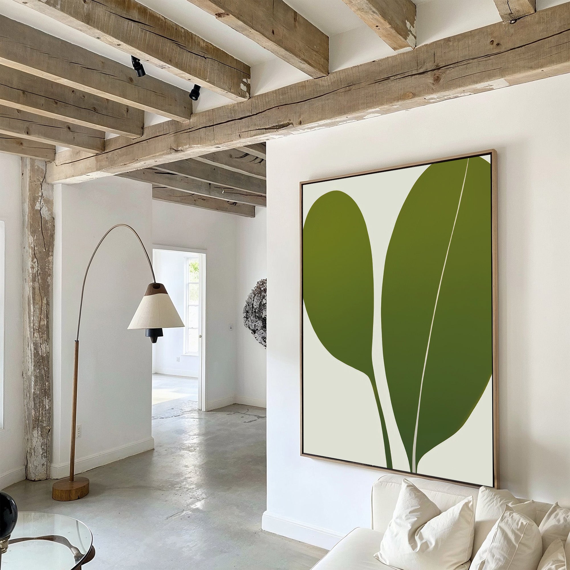 A modern minimalist living room with exposed wooden beams, white walls, a Verdant Duo Abstract Canvas Art piece, a curved floor lamp, and a white sofa with pillows. Natural light enhances the stylish atmosphere.